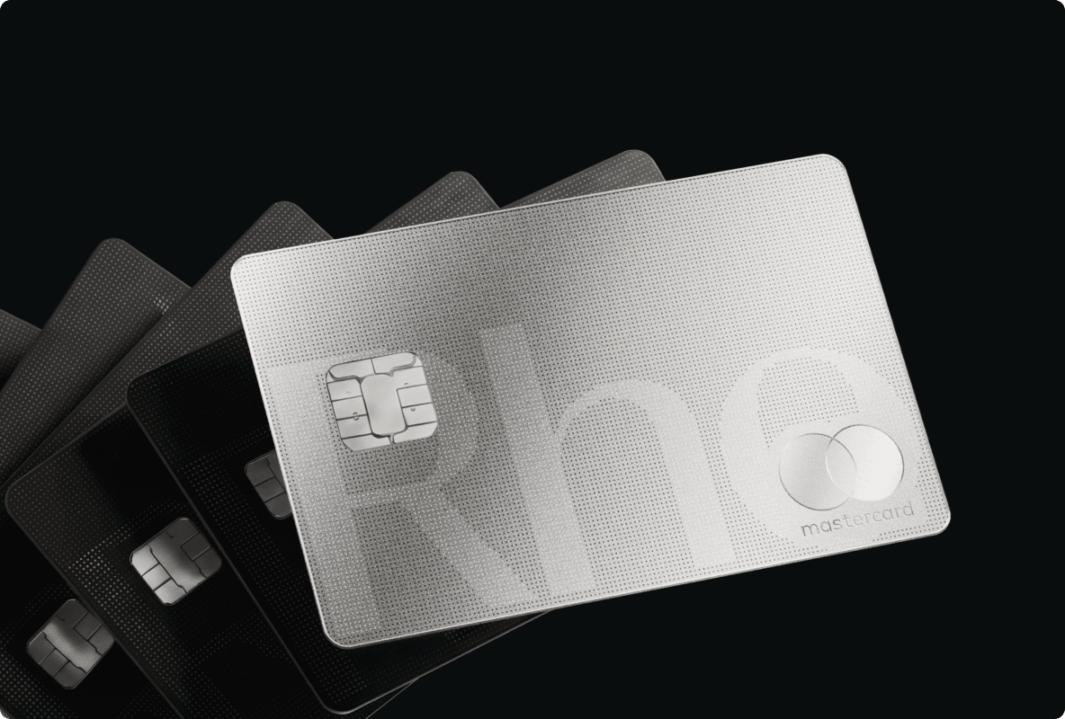 A stack of sleek silver and black bank cards with an embossed chip and Mastercard logo, set against a dark background.