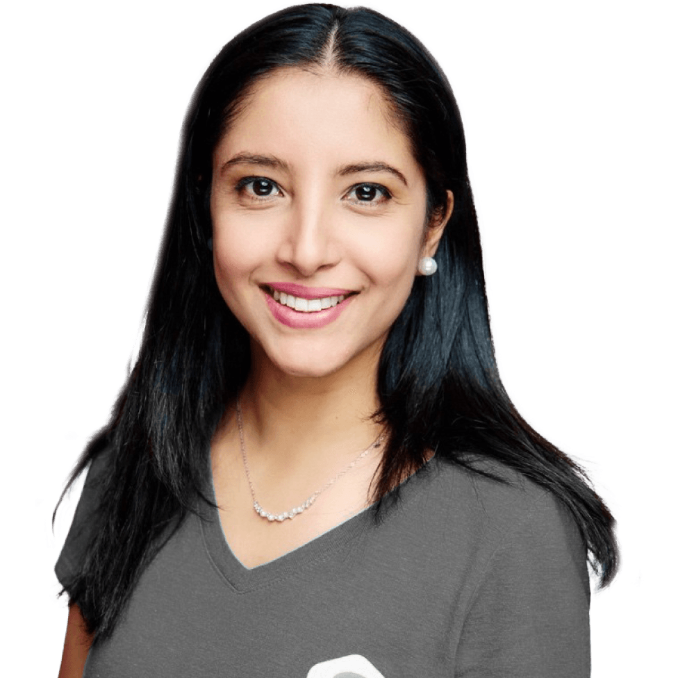Smiling woman with long dark hair, wearing a gray shirt and a pearl necklace, against a plain white background.